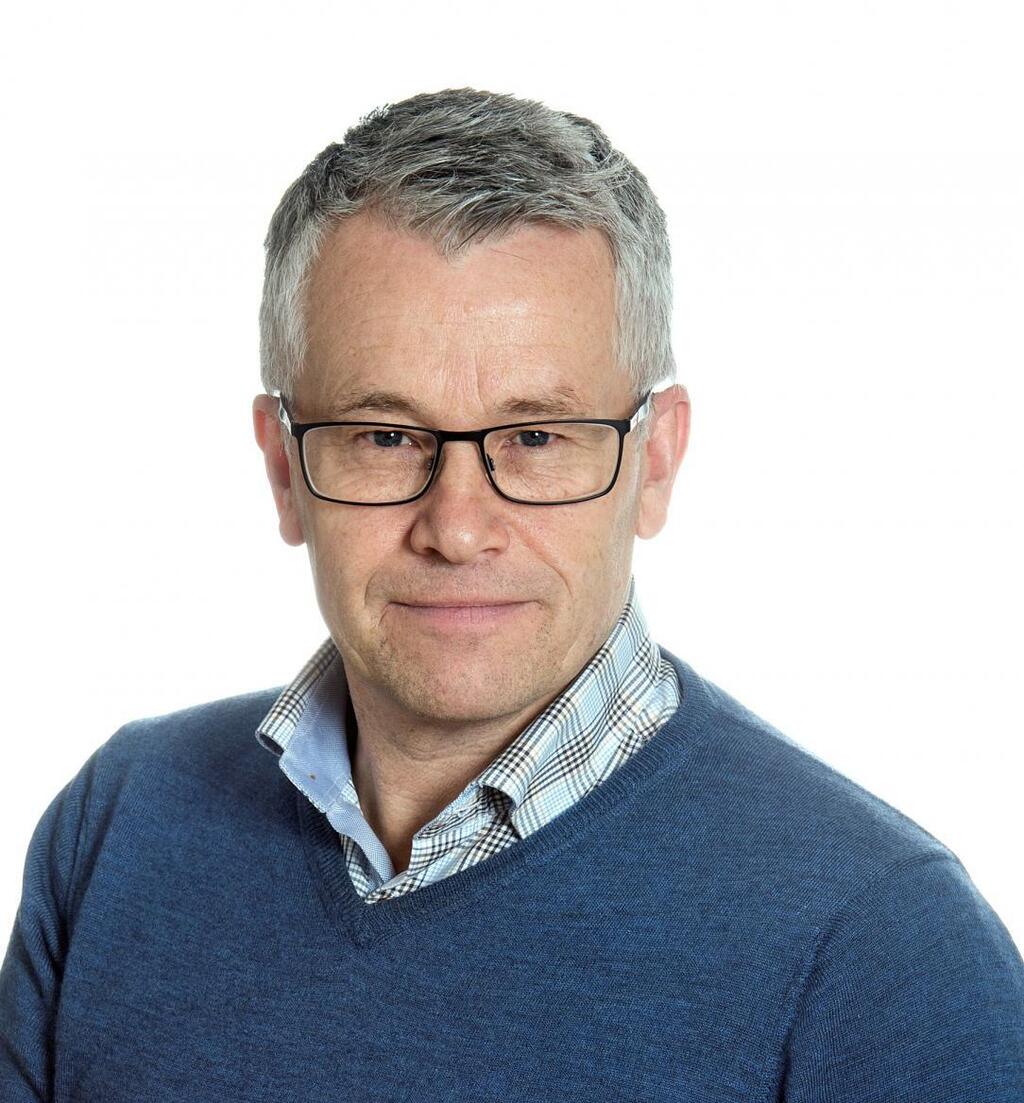 Johan Östling, en leende man i 50årsåldern med grått hår och glasögon mot en vit bakgrund.